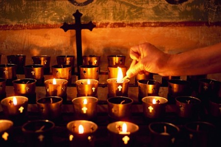 Worshiper Lighting Votive Candle on Altar